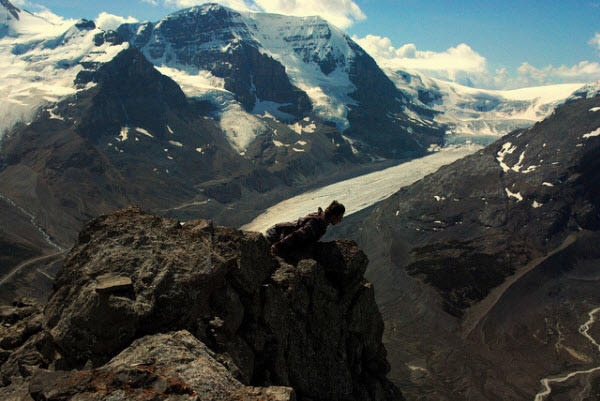 Person planking at a great altitude amidst the mountains